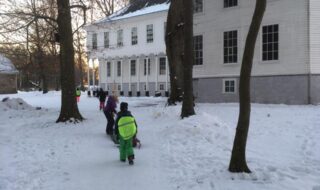 Bilde fra utsiden av Gimle Gård på vinter, avbildet med skolebarn