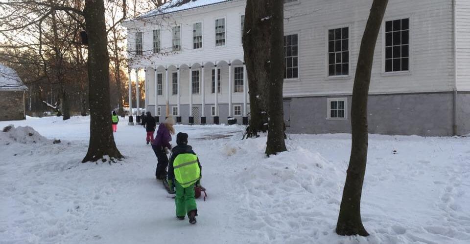 Bilde fra utsiden av Gimle Gård på vinter, avbildet med skolebarn