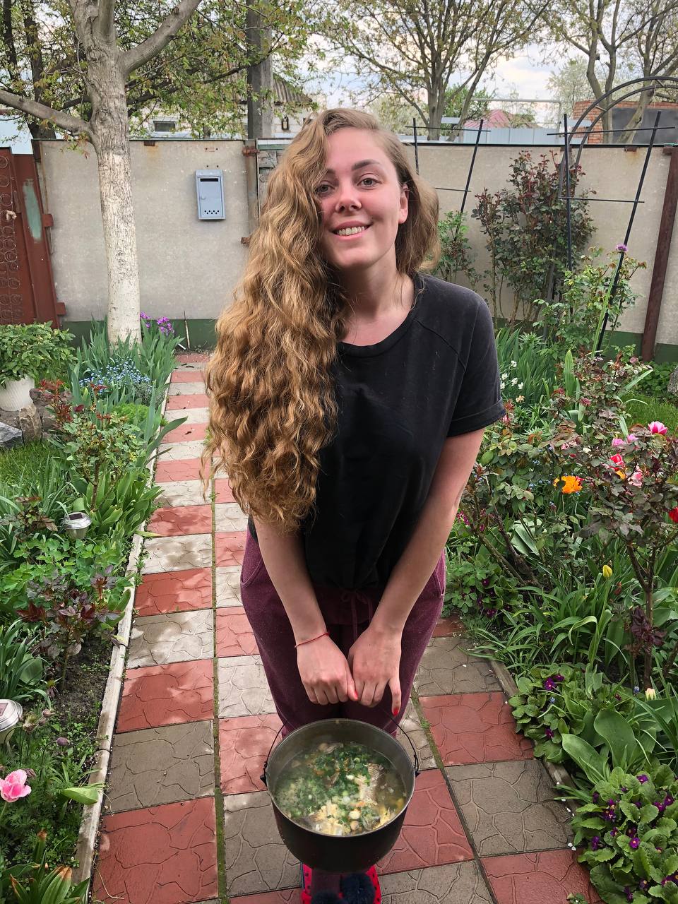 Anna Zolotar i hagen med fiskesuppe med grønnsaker i bøtte