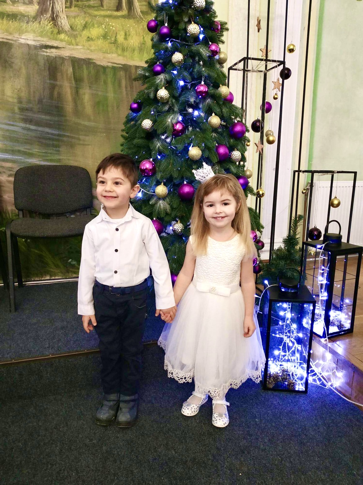 Gutt og jentet står pyntet foran et juletre i Ukraina