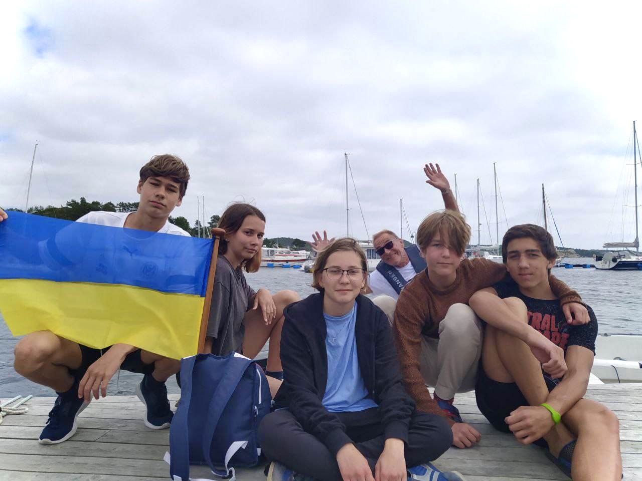 Fem ungdommer med det ukrainske flagget, ser ut som det kan være i havna i Kristiansand