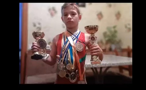 Maksym Poroskym fra Ukraina viser fram medaljer og pokaler han har vunnet i bryting