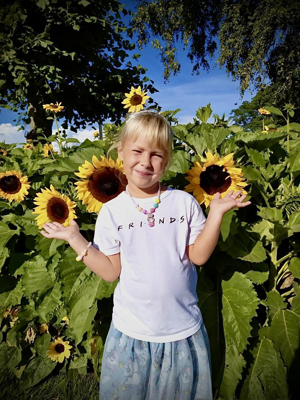 Glad jente foran solsikkeåker