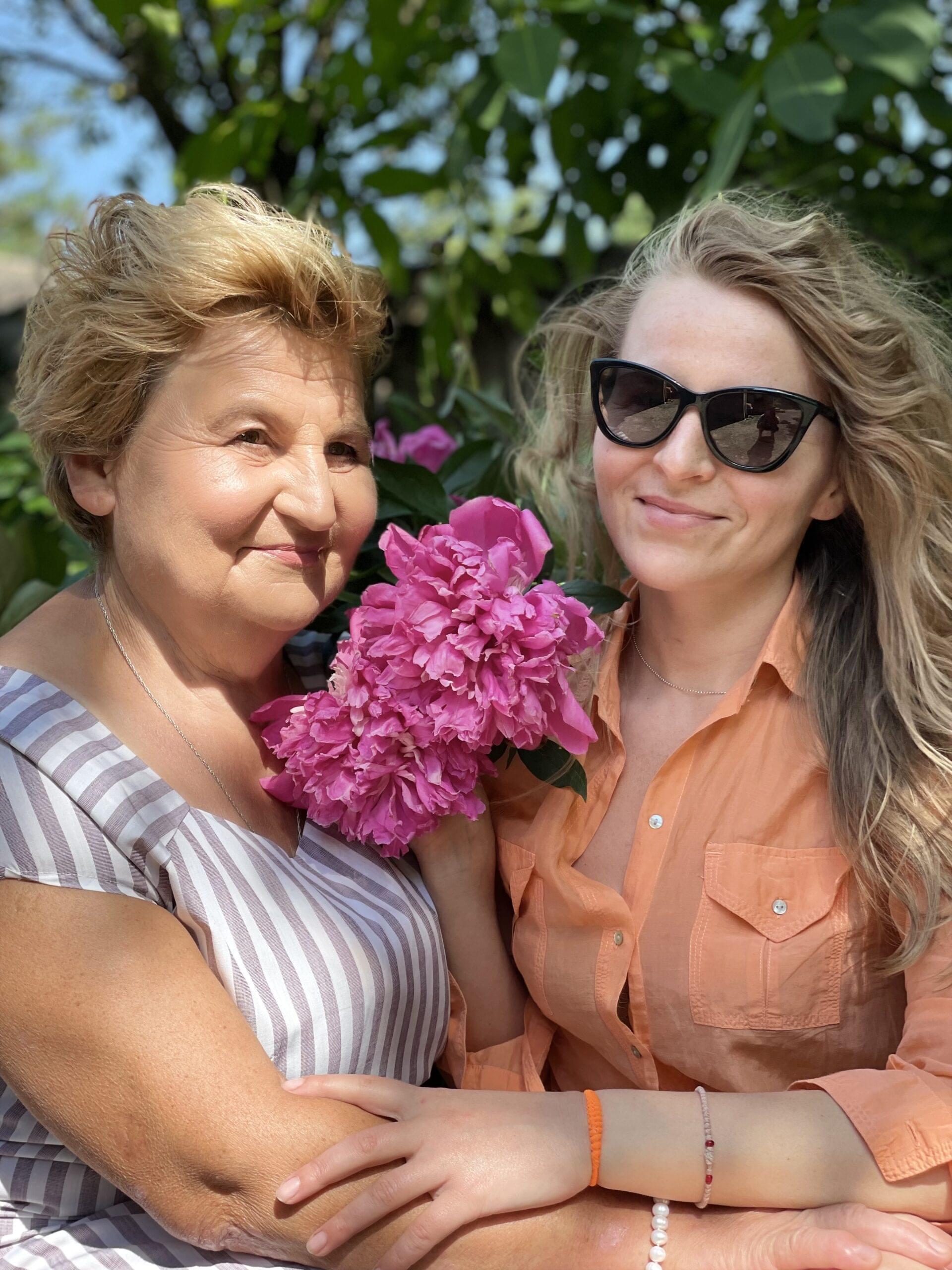 Mamma, datter Yuliia som holder en bukett peoner