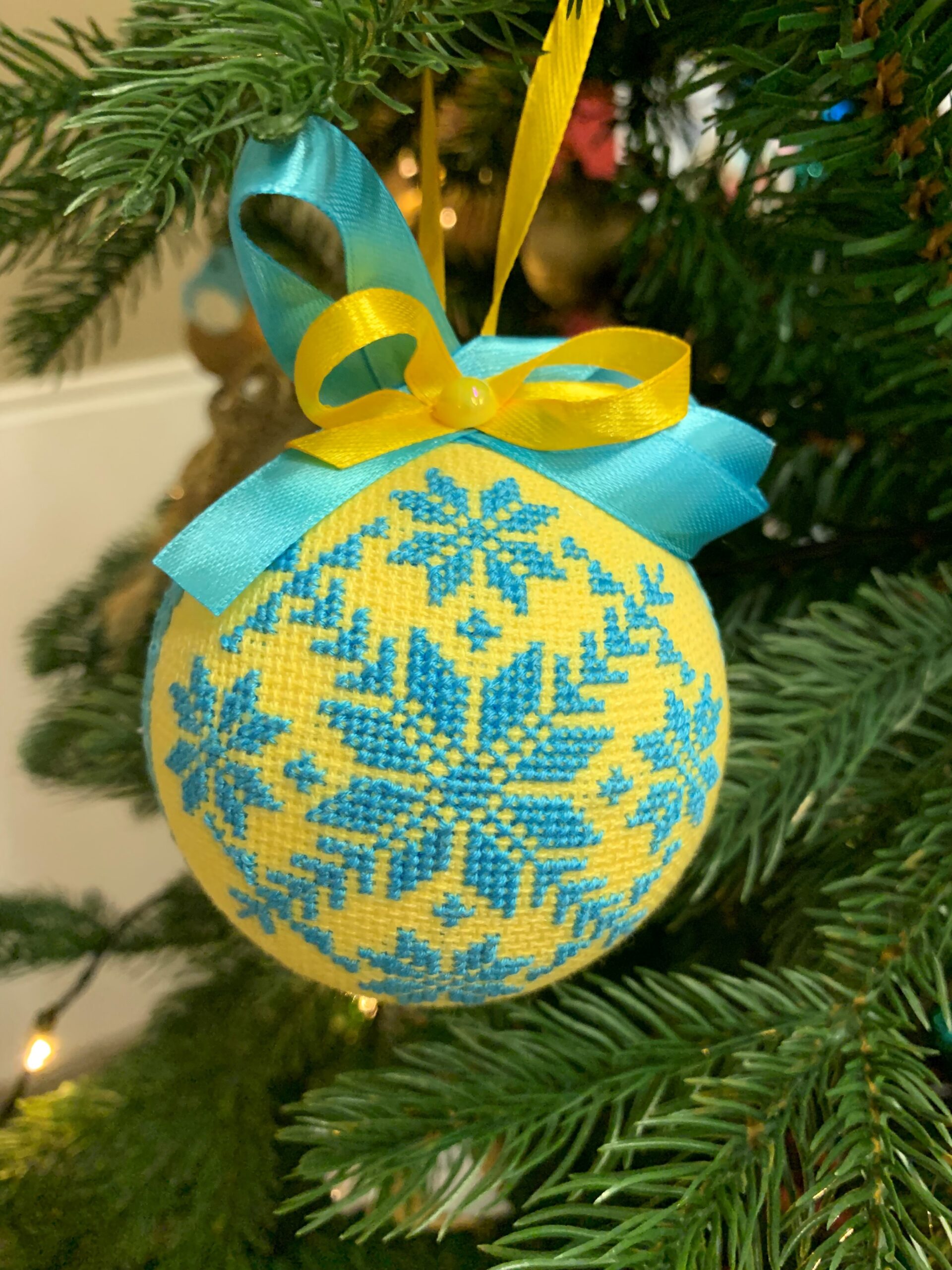 Detaljbilde av en juletrekule på det ukrainske juletreet. Kulen er håndbrodert i de ukrainske fargene, blått og gult.