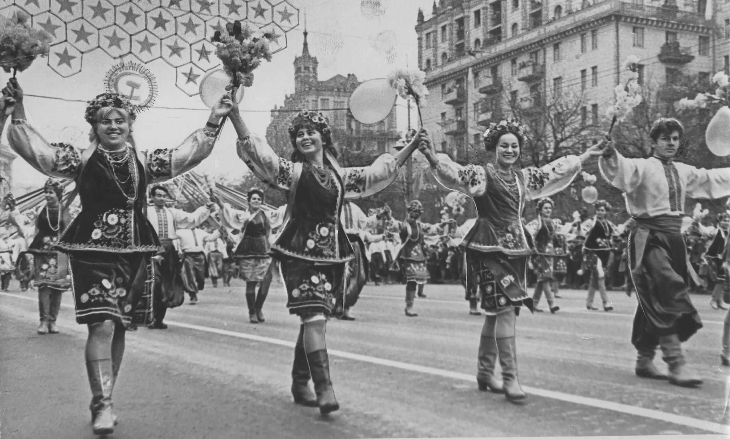 Svart-hvitt-bilde fra et opptog med dansende mennesker i folkedraktliknende antrekk, med knekorte skjørt og støvletter. Bildet er tatt i Kyiv 1967