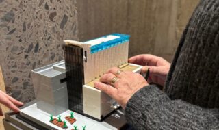 Bilde av to hender som føler seg frem på en liten model av Kunstsilo bygget.